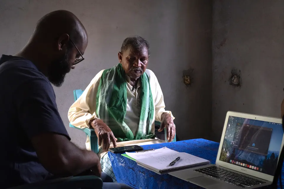 A linguist records a Santali speaker with a laptop and microphone